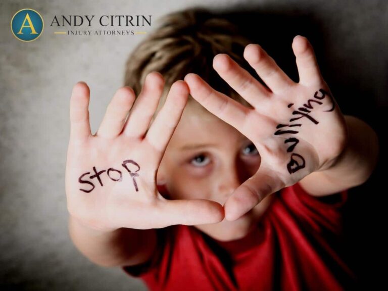 A child holds up their hands with "stop" written on one hand and "bullying" on the other, looking up at the camera.